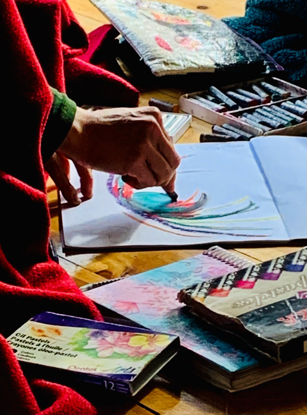 Manos pintando con pasteles sobre un cuaderno