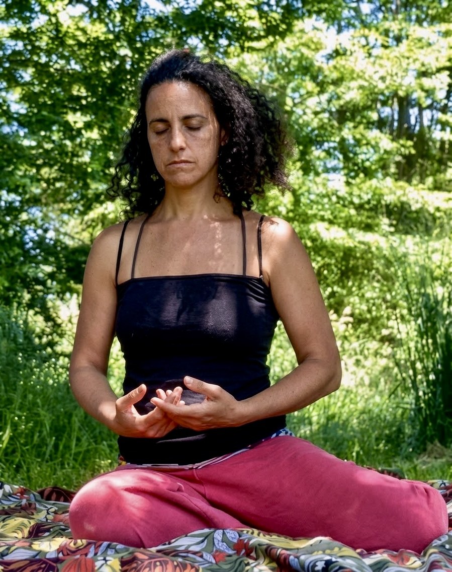 Carla sentada en meditación en un bosque